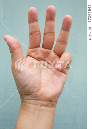 Trigger Finger lock on little finger of woman's front left hand, Suffering from pain, On Blue-grey colour background,  Close up & Macro shot, Office syndrome, Health care concept 57265645