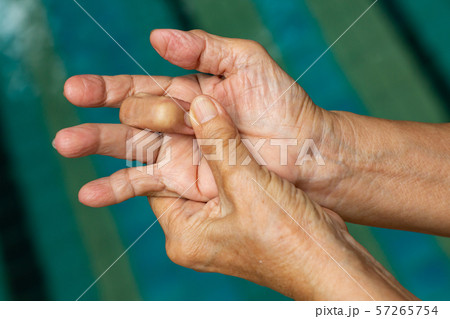 Trigger Finger, Senior woman's left hand massaging her middle finger, Suffering from pain, Close up and macro shot, Swimming pool background, Health care concept Trigger Finger, Senior woman's left hand massaging her middle finger, Suffering from pain, Close up and macro shot, Swimming pool background, Health care concept 57265754