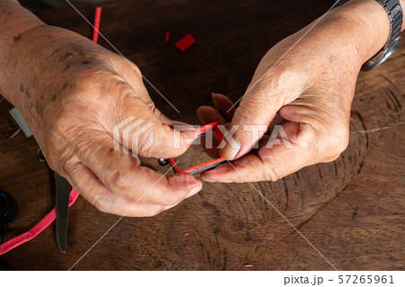 Senior man' s hands to provide Amulet, .Small Buddha image with a metal cap on wood table texture background , Close up & Macro shot, Asian body part, Craftsman processing concept Senior man' s hands to provide Amulet, .Small Buddha image with a metal cap on wood table texture background , Close up & Macro shot, Asian body part, Craftsman processing concept 57265961