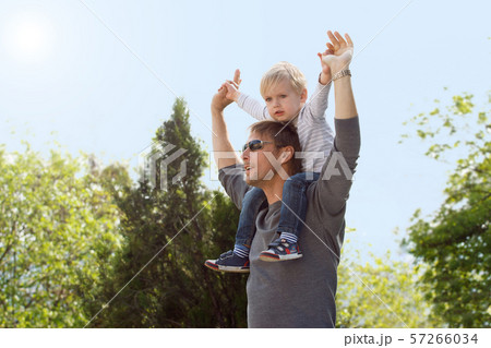 Blond boy sitting on fathers shoulder outdoors Blond boy sitting on fathers shoulder outdoors 57266034