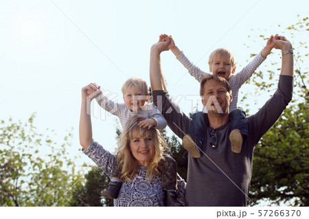 Happy kids sitting on pearents shoulder. 57266370