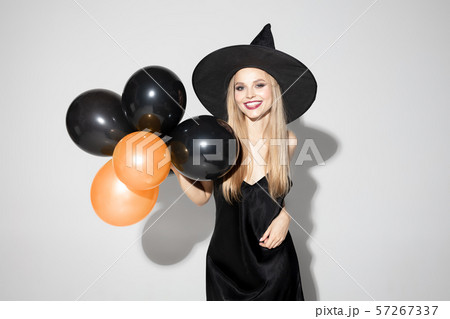 Young woman in hat as a witch on white background 57267337