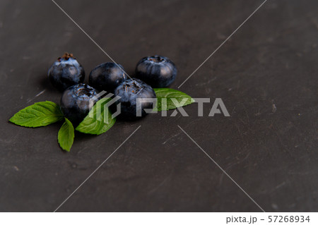 blueberries with green leaves lie on dark black blueberries with green leaves lie on dark black 57268934
