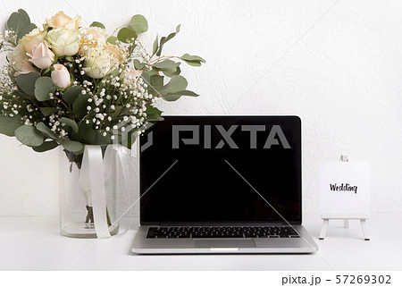 Woman home office desk with laptop and roses bouquet 57269302
