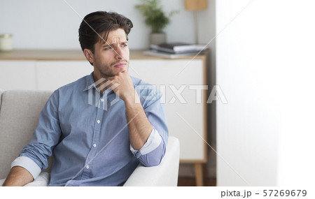 Guy Thinking Looking Aside Sitting On Couch At Home Guy Thinking Looking Aside Sitting On Couch At Home 57269679