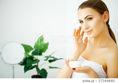 Beautiful model applying cosmetic cream treatmen on her face Beautiful model applying cosmetic cream treatmen on her face 57269682