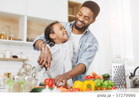 Dad teaching little girl how to cut vegetables Dad teaching little girl how to cut vegetables 57270060