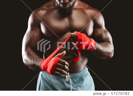 Professional black sportsman rolling boxing wraps over wrists 57270782