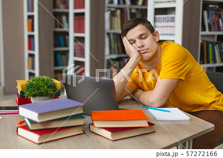 Male student sleeping at workplace in college library Male student sleeping at workplace in college library 57272166