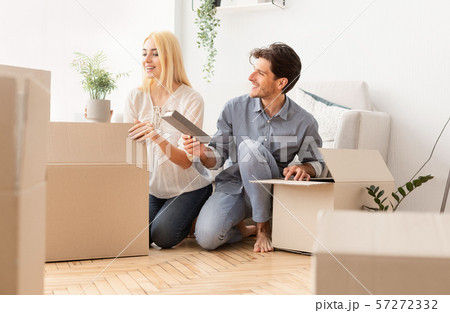 Young Spouses Unpacking Moving Boxes In New House After Relocation Young Spouses Unpacking Moving Boxes In New House After Relocation 57272332