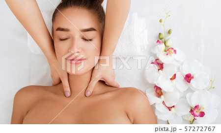 Woman getting neck massage, relaxing with orchid flowers nearby Woman getting neck massage, relaxing with orchid flowers nearby 57272767