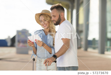 Happy couple looking at boarding pass checking departure time Happy couple looking at boarding pass checking departure time 57273670