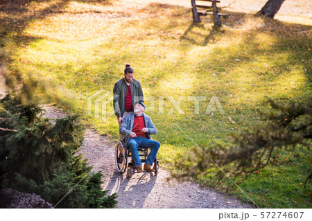 Senior father with wheelchair and his son on walk in nature. 57274607