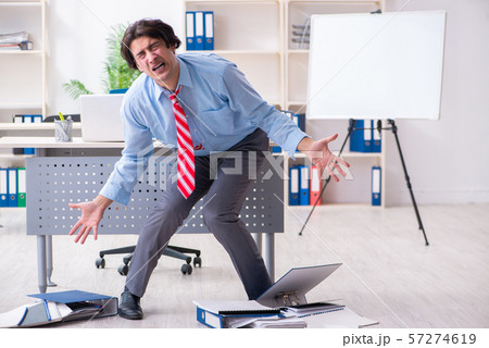 Young male employee unhappy with excessive work 57274619