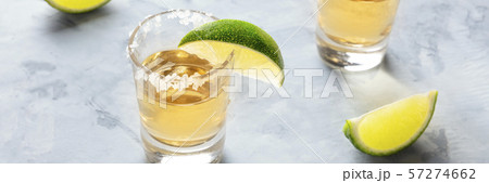 Golden tequila shots with lime slices and salt rims, a panoramic photo 57274662
