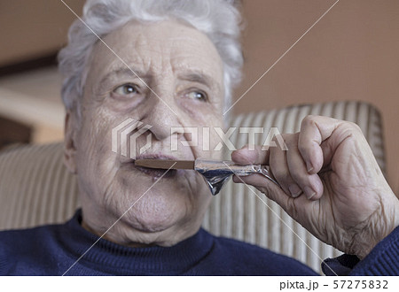 senior woman eating a chocolate bar senior woman eating a chocolate bar 57275832