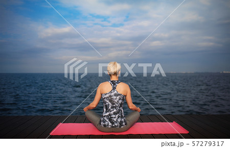 A rear view of young sportswoman doing yoga exercise on beach. Copy space. 57279317