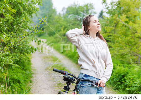 Young woman riding bicycle in summer city park outdoors. Active people. Hipster girl relax and rider Young woman riding bicycle in summer city park outdoors. Active people. Hipster girl relax and rider 57282476