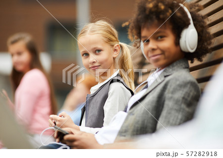 Schoolgirl with her classmate outdoors 57282918