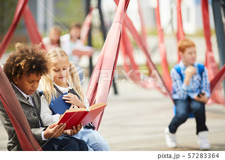 School children reading books outdoors School children reading books outdoors 57283364