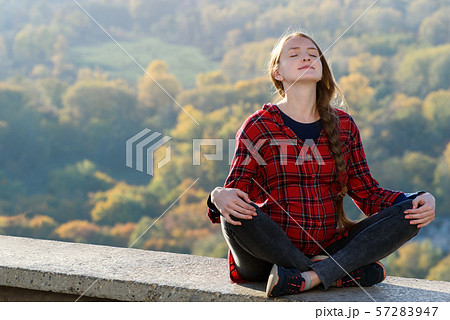Pregnant woman sits on a hill with her eyes 57283947