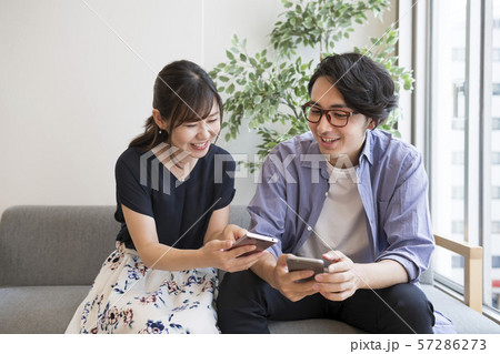 スマートフォンを見ながら話す男女 スマートフォンを見ながら話す男女 57286273
