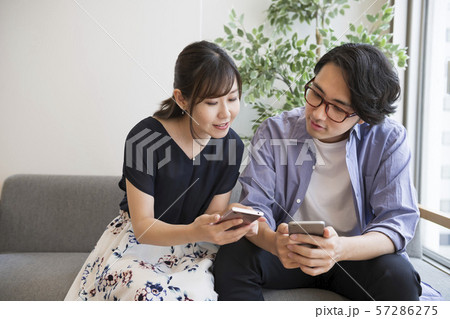 スマートフォンを見ながら話す男女 57286275