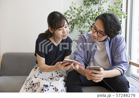 スマートフォンを見ながら話す男女 57286276