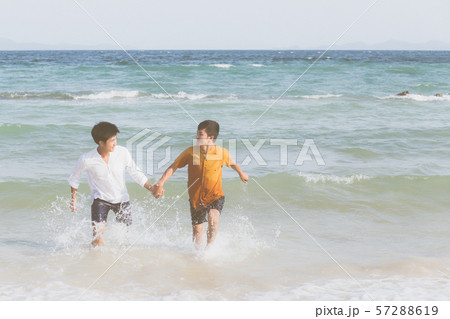 Homosexual portrait young asian couple running with cheerful together on beach in summer Homosexual portrait young asian couple running with cheerful together on beach in summer 57288619