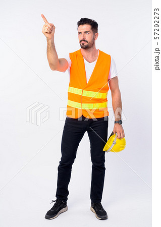 Full body shot of young bearded man construction worker thinking and directing 57292273