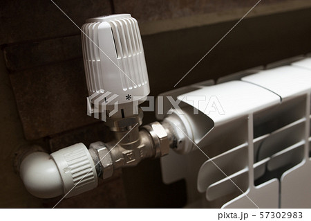 White radiator in the bathroom close-up. Heating. Tiled gray wall. White radiator in the bathroom close-up. Heating. Tiled gray wall. 57302983