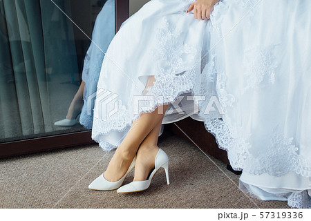 beautiful bride in a dress puts on white shoes 57319336