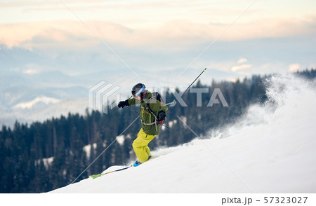 Skier descending from snow-covered high mountain peak. Extreme back-country skiing concept Skier descending from snow-covered high mountain peak. Extreme back-country skiing concept 57323027
