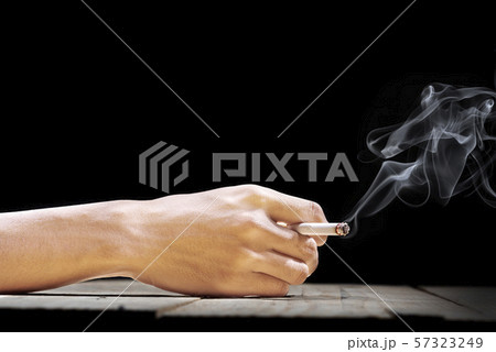 Hand holding a cigarette on wooden table 57323249
