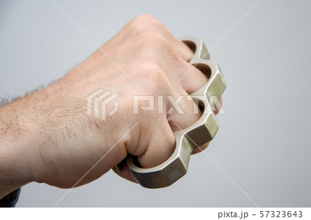 Man strikes brass knuckles on a light background, a prohibited weapon in a fight 1 57323643