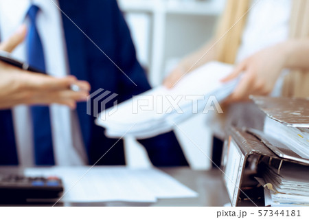 Binders with papers waiting to be processed with businessman or bookkeeper back in blur. Accounting Binders with papers waiting to be processed with businessman or bookkeeper back in blur. Accounting 57344181