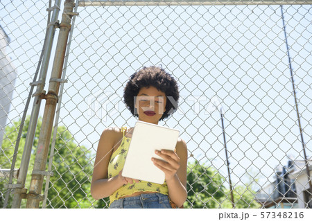 Young woman using digital tablet by wire fence 57348216
