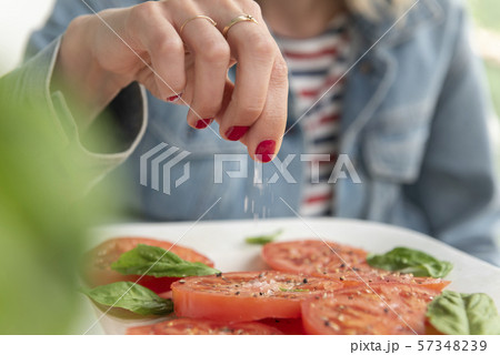 Woman sprinkling salt on tomatoes Woman sprinkling salt on tomatoes 57348239