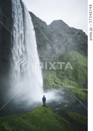 Man standing by Seljalandsfoss waterfall in Iceland 57348748