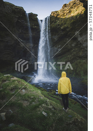 Man wearing yellow raincoat by Kvernufoss waterfall in Iceland 57348751