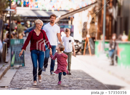 Young family with two small children walking outdoors in town on holiday. 57350356