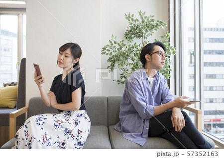 自分のスマートフォンを持って反対方向を向く男女 自分のスマートフォンを持って反対方向を向く男女 57352163