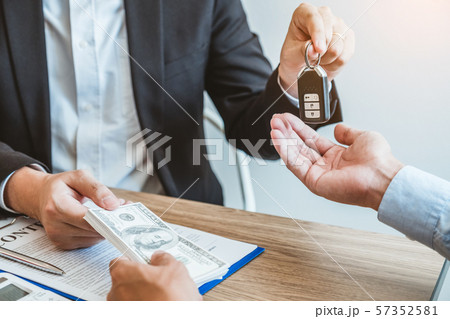 Sale agent giving Car key to customer and sign 57352581
