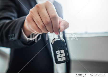 Sale agent giving Car key to customer and sign 57352606
