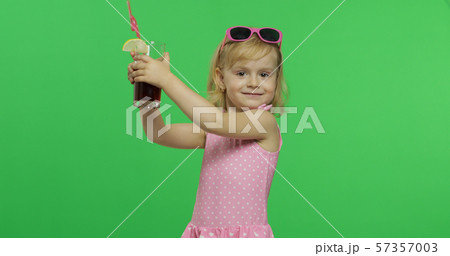 Child in pink swimsuit holds juice cocktail with drinking straw. Chroma Key 57357003