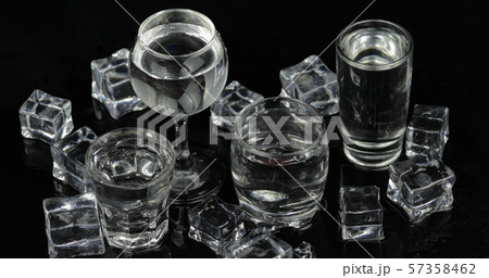 Shots of vodka with ice cubes against black background 57358462