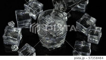 Pouring up shot of vodka from a bottle into glass. Black background Pouring up shot of vodka from a bottle into glass. Black background 57358464