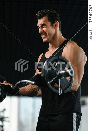 Muscular man training with barbell in gym 57360708