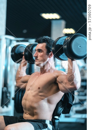 bodybuilder doing the exercises with dumbbells 57360709