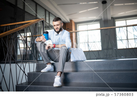 Bearded man enjoying little break drinking coffee on stairs Bearded man enjoying little break drinking coffee on stairs 57360803